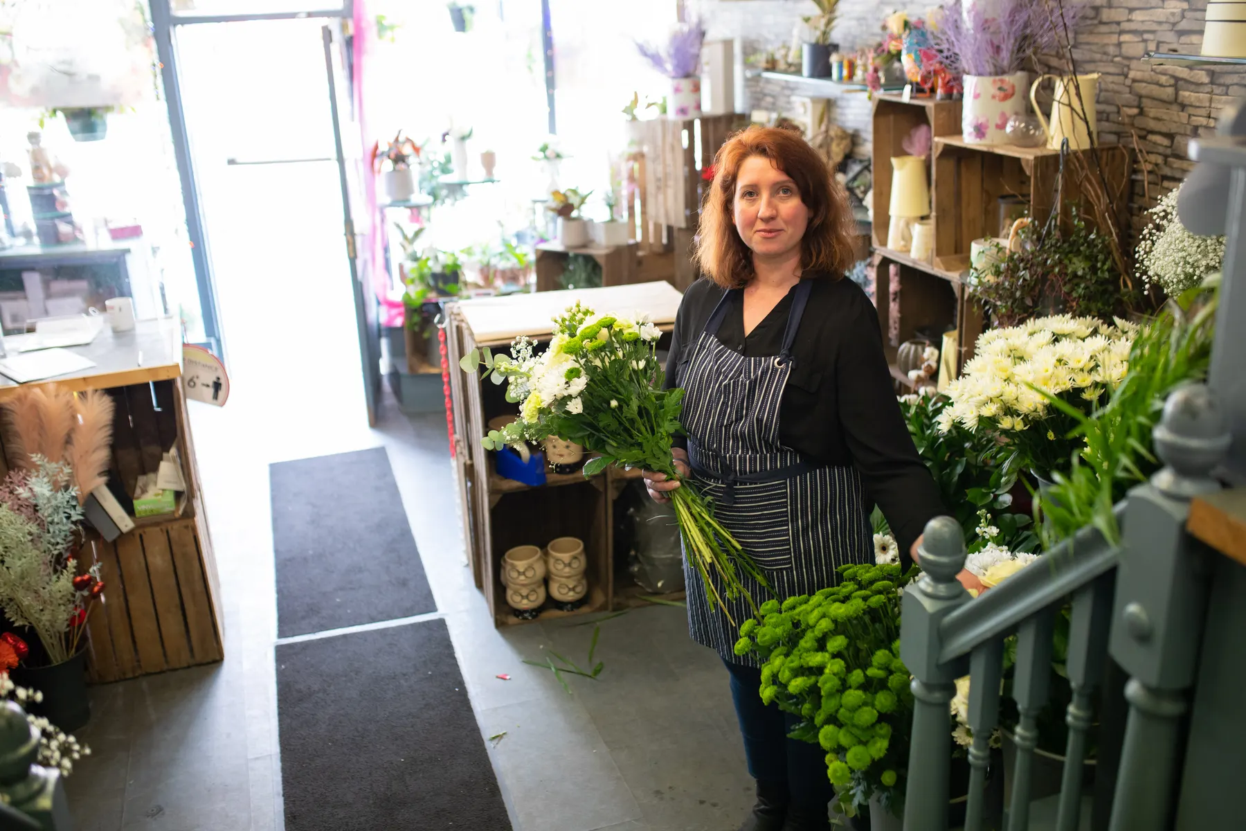 Florist gathering stems in the doorway of a bright flower shop