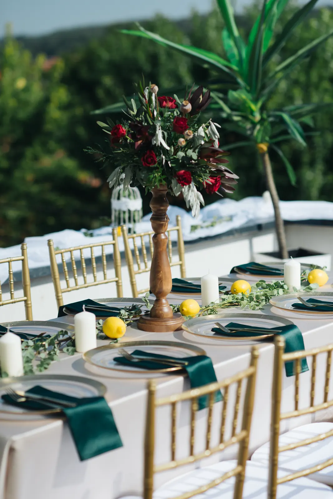 Tall floral centrepiece on a long dining table set with green napkins