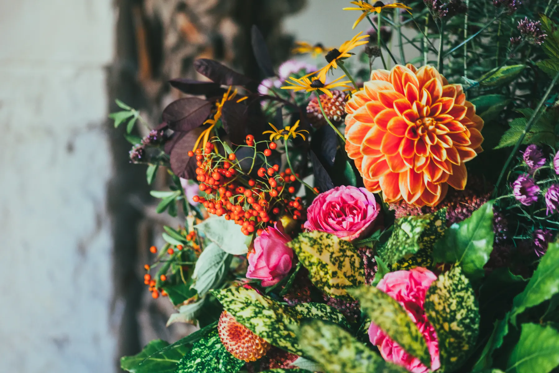 Warm orange dahlias and rowan berries in a seasonal arrangement
